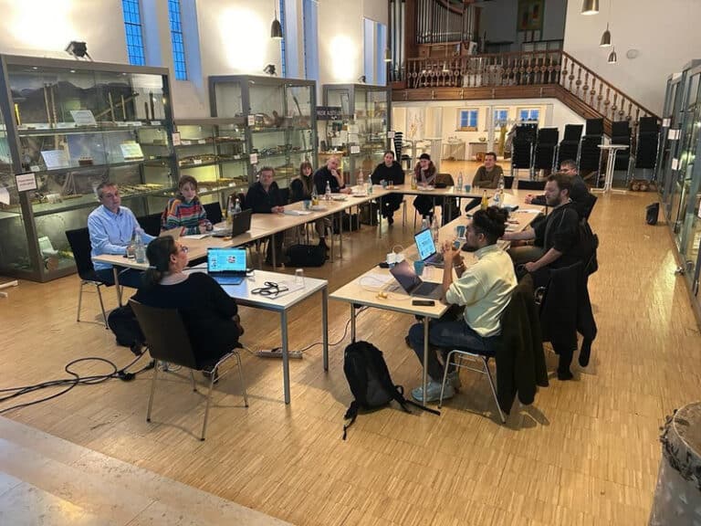 Kostima Mitglieder sitzen um einen Tisch herum bei einem Workshop