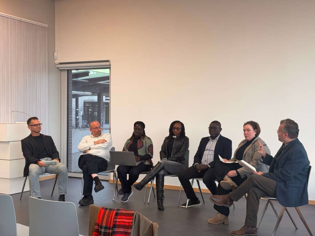 7 Menschen sitzen in einem offenen Halbkreis während Diskussionsrunde